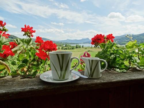 two coffee cups sitting on a table with flowers at Sunnhof in Oberhofen am Irrsee