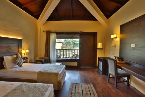 a hotel room with two beds and a desk at Jungle Villa Resort - Near Chitwan National Park in Chitwan