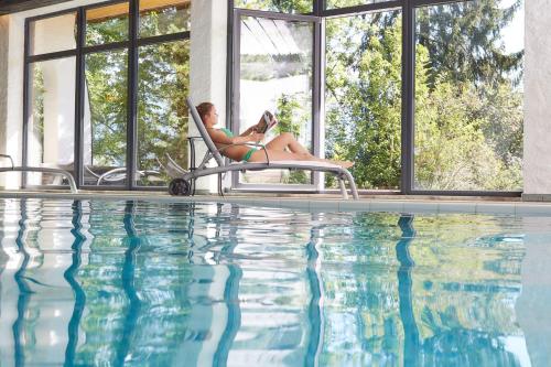a woman sitting in a chair next to a swimming pool at freistil Boutiquehotel in Sonthofen