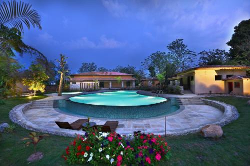 a swimming pool in a yard with flowers at Jungle Villa Resort - Near Chitwan National Park in Chitwan