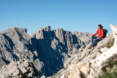 a man sitting on the edge of a mountain at Moseralm Dolomiti Spa Resort in Nova Levante