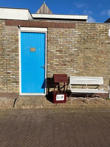 een blauwe deur en een bank naast een bakstenen gebouw bij Studio Chilltime Harlingen in Harlingen