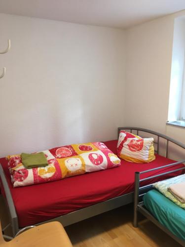 un letto con coperta rossa e cuscini sopra di Fe wo Viktoria a Lahr