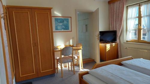 a bedroom with a bed and a desk and a television at Gasthof Russenbräu in Tiefenbach