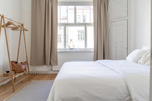 a bedroom with a white bed and a window at Roost Huvilakatu in Helsinki