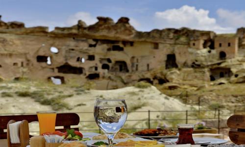 a table with a plate of food and a wine glass at Seki Cave Suites in Goreme