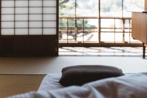 Bett in einem Zimmer mit Fenstern in der Unterkunft クジラ別館 in Onomichi