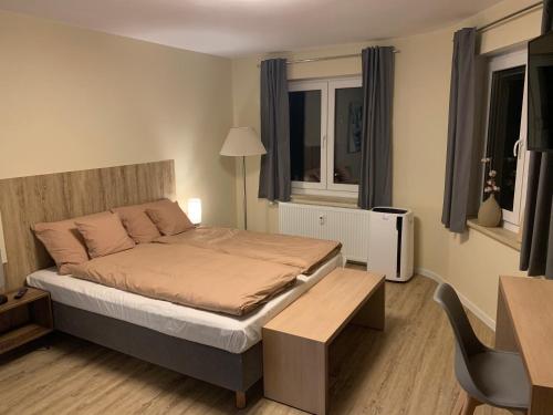 a bedroom with a bed and a desk and a chair at Pension Am Amtsgericht in Eiterfeld