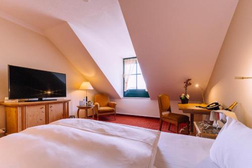 a bedroom with a bed and a tv and a desk at Atomis Hotel Munich Airport by Mercure in Oberding