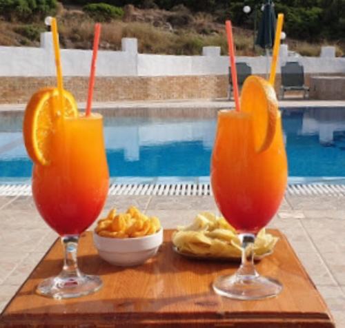 dos vasos de zumo de naranja y patatas fritas en una mesa junto a una piscina en Hotel Orama-Matala, en Matala