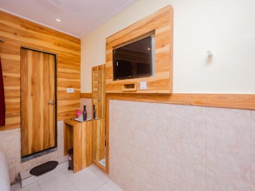 a bathroom with a flat screen tv on the wall at Aman Hotel near CST in Mumbai