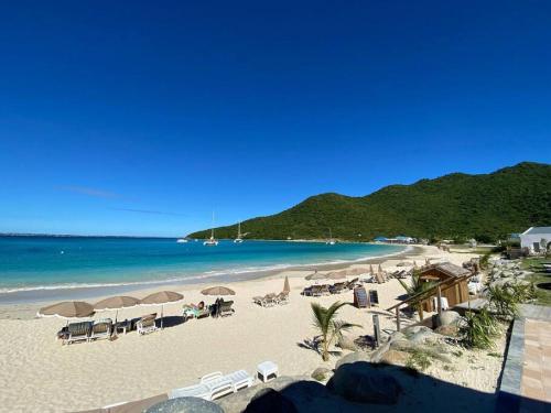 a beach with chairs and umbrellas and the ocean at From Paris to SXM - luxury next to Anse Marcel Beach in Anse Marcel 