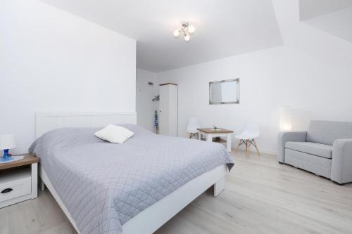 a white bedroom with a bed and a chair at Krab in Rewal