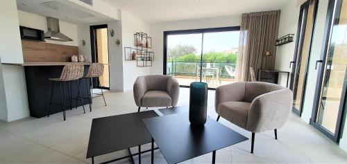 a living room with two chairs and a table and a room at Résidence Storia d'Estate in LʼÎle-Rousse