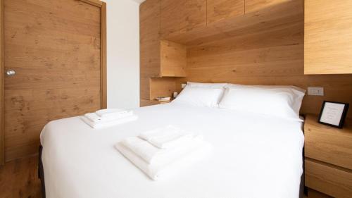 a bedroom with a white bed with a wooden wall at Italianway - Al Forte 6 in Valdisotto