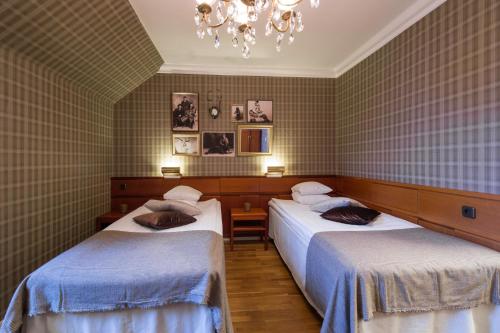 a bedroom with two beds and a chandelier at Stadshotellet Lidköping in Lidköping