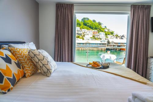 a bed with a tray of food on it with a window at Portbyhan Hotel in Looe