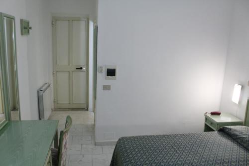 a room with a bed and a door and a table at Hotel Castiglione in Ischia