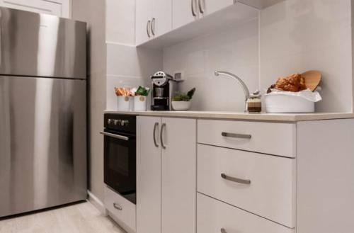 une cuisine avec des armoires blanches et un réfrigérateur en acier inoxydable dans l'établissement Ben Yehuda Pearl - יציאה במוצאי שבת וחג ללא עלות, à Jérusalem