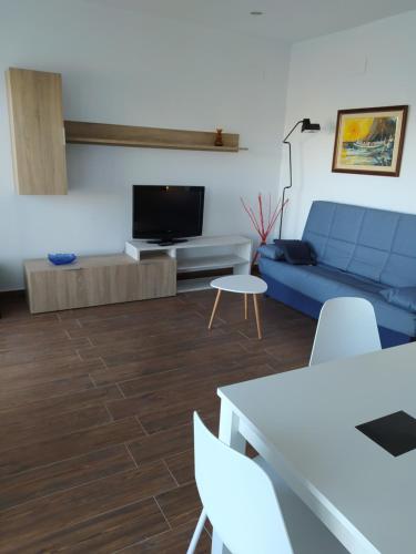 uma sala de estar com um sofá azul e uma televisão em Ca la Nuri Pis 4 vistas al mar em Llançà