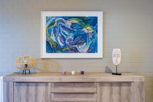 a table with a painting and a mask on it at SHAMBALLA logies nieuw en zeer verzorgd appartement met voortuin en terras in Deinze