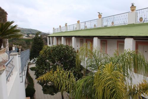 a white building with a green roof and plants at Hotel Castiglione in Ischia