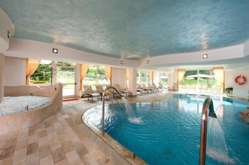 una gran piscina cubierta con bañera de hidromasaje y tobogán de agua en Centro Pineta Family Hotel & Wellness en Pinzolo