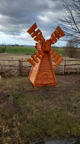 a wooden windmill sitting in the grass near a fence at Viesu māja Kaķis krūzē in Folvarcīši