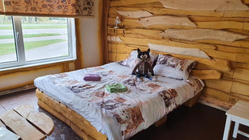 Una cama en una cabaña de madera con un osito de peluche. en Viesu māja Kaķis krūzē, en Folvarcīši