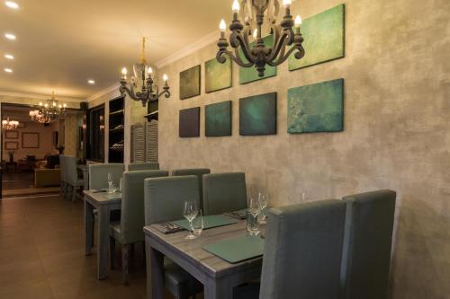 a dining room with tables and chairs and paintings on the wall at La Maison by Dia Hotels and Homes in Panaji
