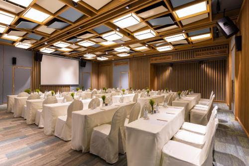 a conference room with white tables and chairs and a screen at Fusion Suites Vung Tau in Vung Tau