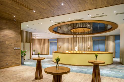 a lobby of a hotel with two tables and a reception desk at Fusion Suites Vung Tau in Vung Tau