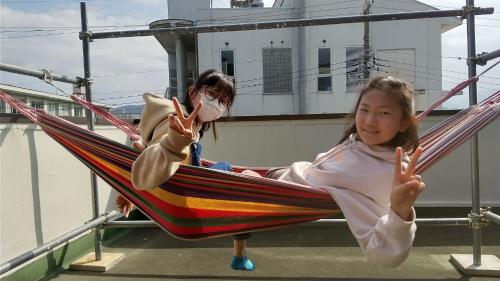 two young girls sitting in a hammock at 海辺のゲストハウスーぽかぽか村ー in Ise