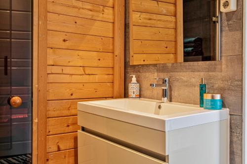 a bathroom with a white sink and a wooden wall at Apartment De Stranding in Egmond aan den Hoef