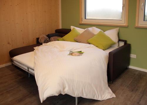 een groot bed met witte lakens en kussens bij Hollweck´s Landoase in Pilsach