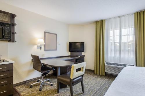 a hotel room with a desk and a table and chairs at Candlewood Suites Virginia Beach Town Center by IHG in Virginia Beach