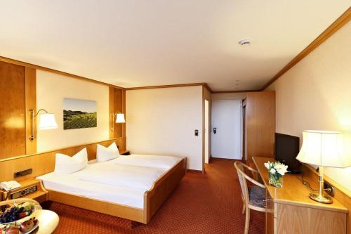 ein Hotelzimmer mit einem großen Bett und einem Schreibtisch in der Unterkunft Hotel-Restaurant Rebstock in Vogtsburg