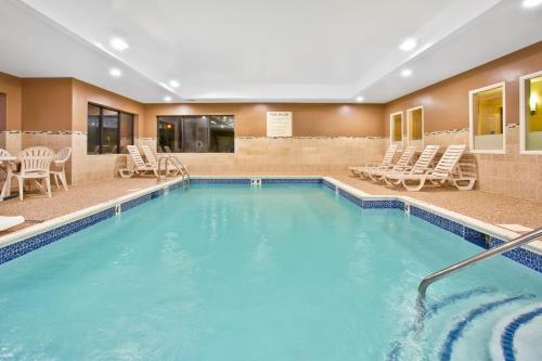 a pool in a hotel with chairs and a table at Holiday Inn Express & Suites Bradley Airport by IHG in Windsor Locks