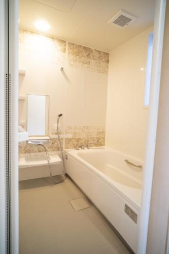 a white bathroom with a tub and a sink at 渡 - Duo Okinawa in Onna