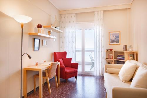 a living room with a red chair and a table at Metaxa Seafront Apartment in Perea