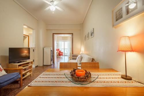 a living room with a table and a tv at Metaxa Seafront Apartment in Perea