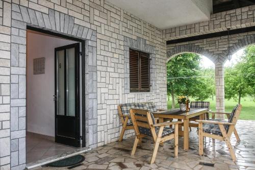a patio with a table and chairs in a stone wall at Apartments Suzy in Vantačići