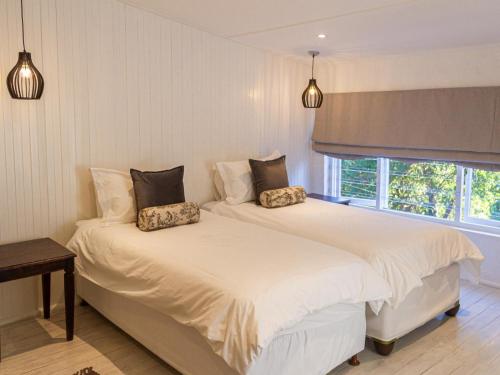 two twin beds in a room with a window at River House in Plettenberg Bay