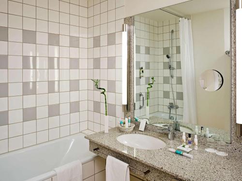 a bathroom with a sink and a tub at Mercure Hotel am Messeplatz Offenburg in Offenburg