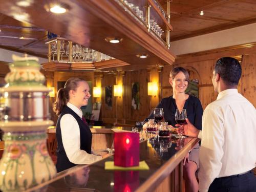 a group of people standing around a bar with wine glasses at Mercure Hotel am Messeplatz Offenburg in Offenburg