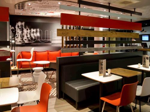 a restaurant with orange chairs and desks and tables at ibis Honfleur in Honfleur