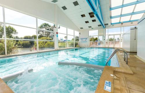 una gran piscina cubierta con bañera de hidromasaje en Mobil home climatisé ETANG DE BESSE, en La Parée Preneau