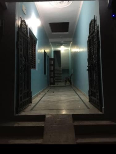 a hallway with blue walls and an open door at Vamoose Cherie Homestay in Khajurāho