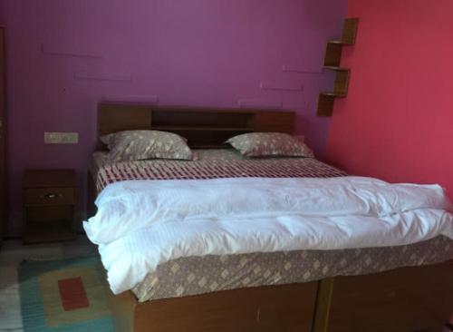 a bedroom with a bed with a pink wall at Vamoose Cherie Homestay in Khajurāho