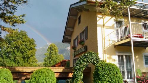 a building with a rainbow in the background at Parkhotel Ruhpolding inklusive Chiemgaukarte in Ruhpolding
